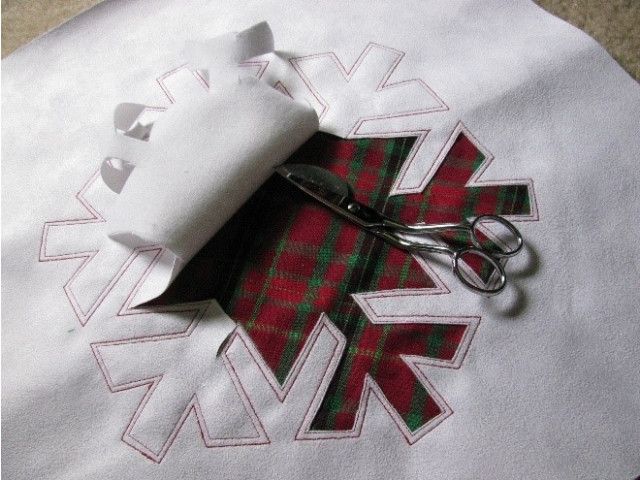 a pair of scissors sitting on top of a piece of white fabric with red and green designs