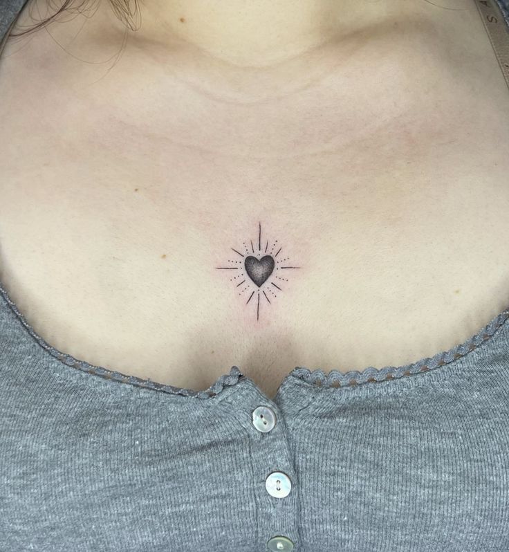 a woman's chest with a small heart tattoo on the left side of her stomach