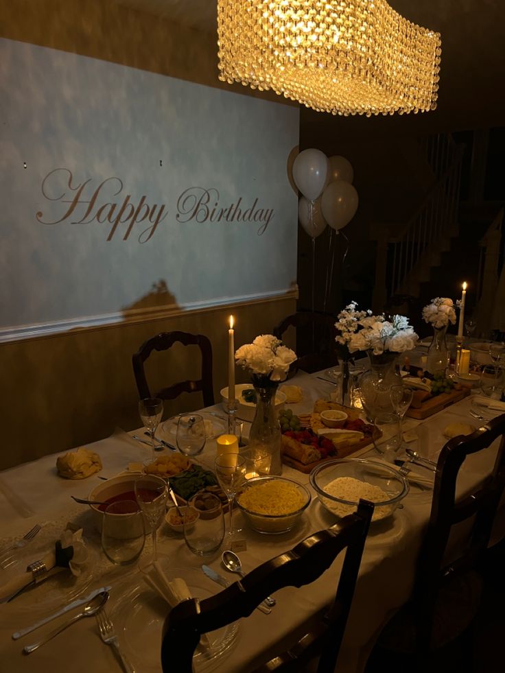 a table set for a birthday party with candles and food