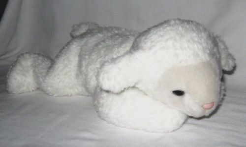 a white stuffed animal laying on top of a bed