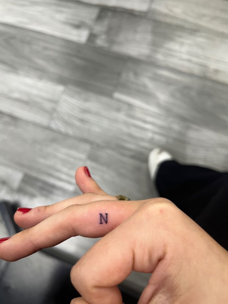 a woman's hand with a small n tattoo on it