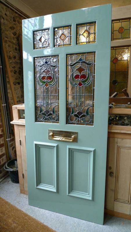 a blue door with stained glass panels on the top and bottom panel, in front of a kitchen