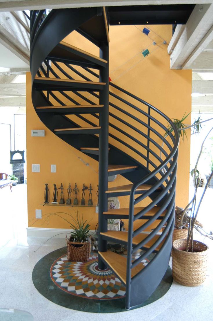 a spiral staircase in the middle of a room with potted plants on the floor