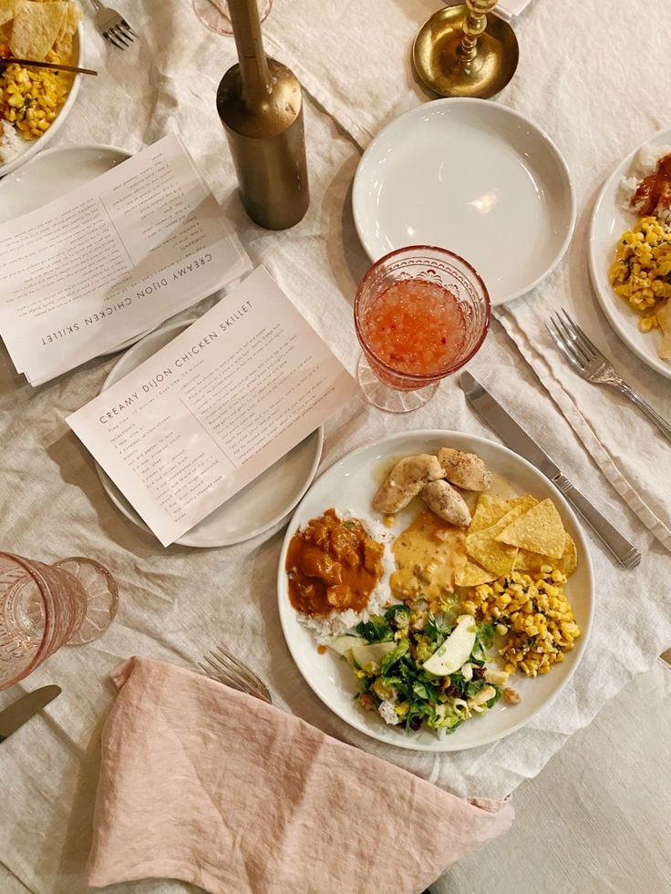 an assortment of food on a table with utensils and menus next to it