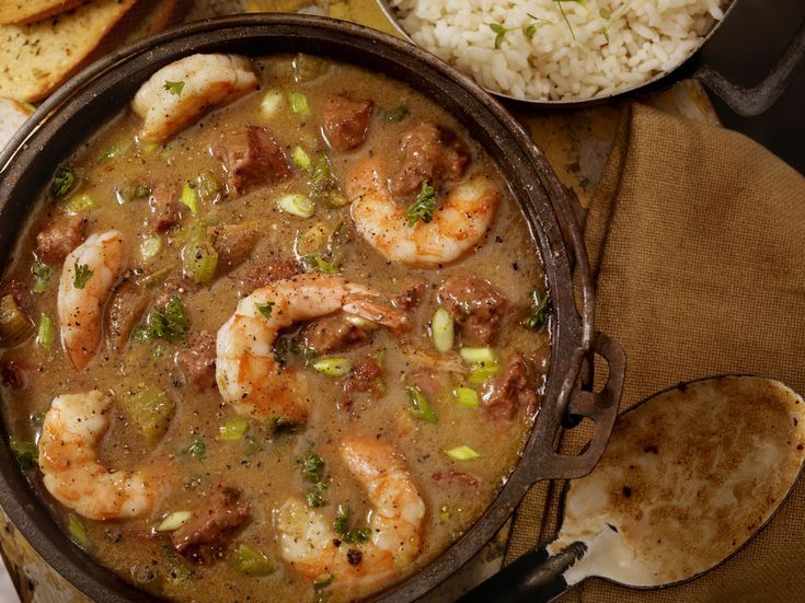 a pan filled with shrimp and rice next to some pita bread on a table