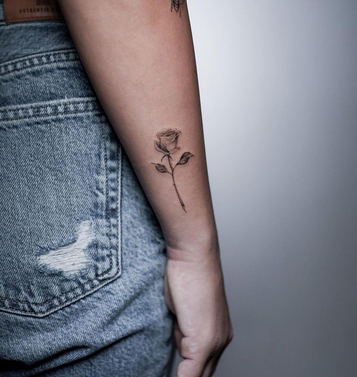 a woman's arm with a rose tattoo on the left side of her right arm