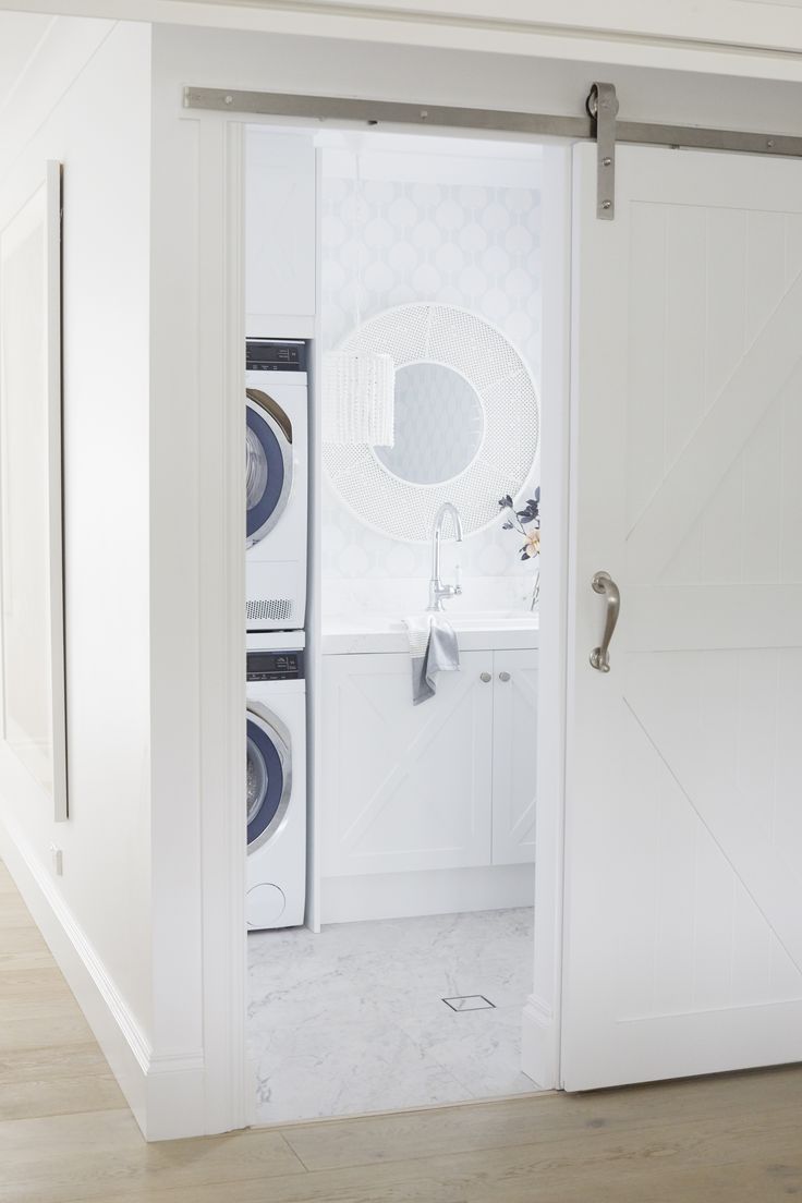 an open door leading to a washer and dryer in a white laundry room