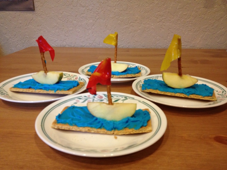 three plates with small sailboats on them and blue icing in the shape of an apple