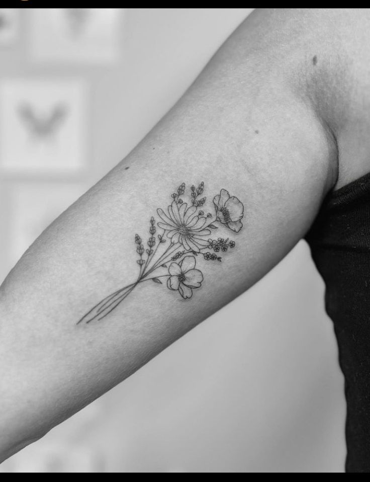 a black and white photo of a woman's arm with flowers tattooed on it