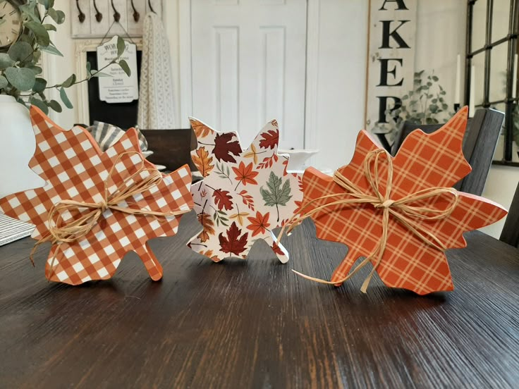 three decorative fall leaves are sitting on a table