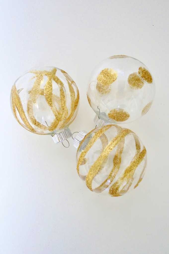 three glass ornaments with gold glitter on them