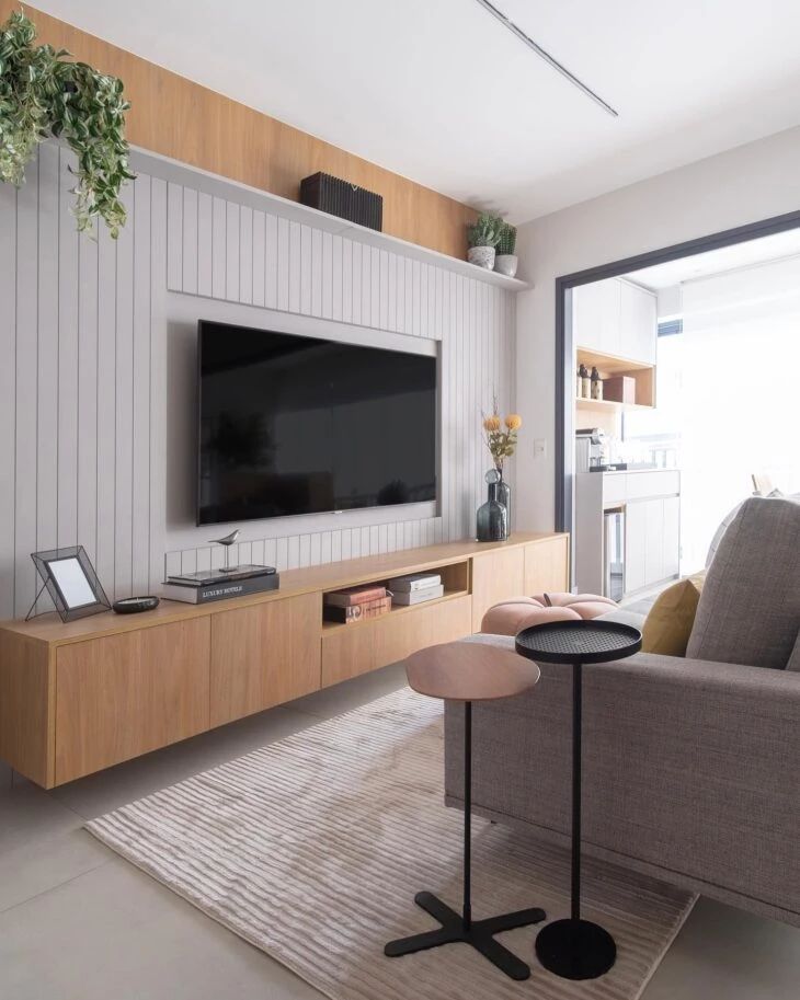 a living room with a couch, coffee table and television on the wall in front of it