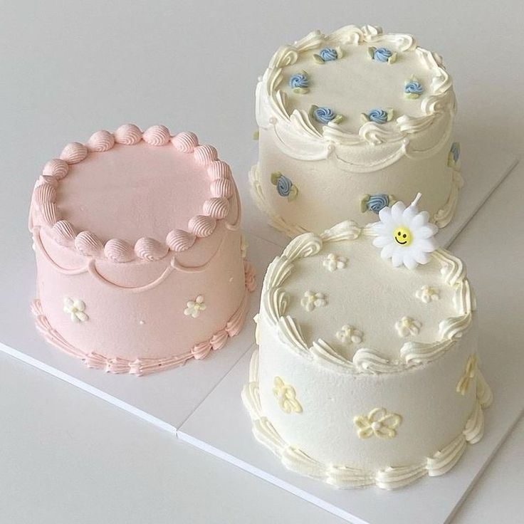 three decorated cakes sitting next to each other on a white counter top with blue and pink frosting