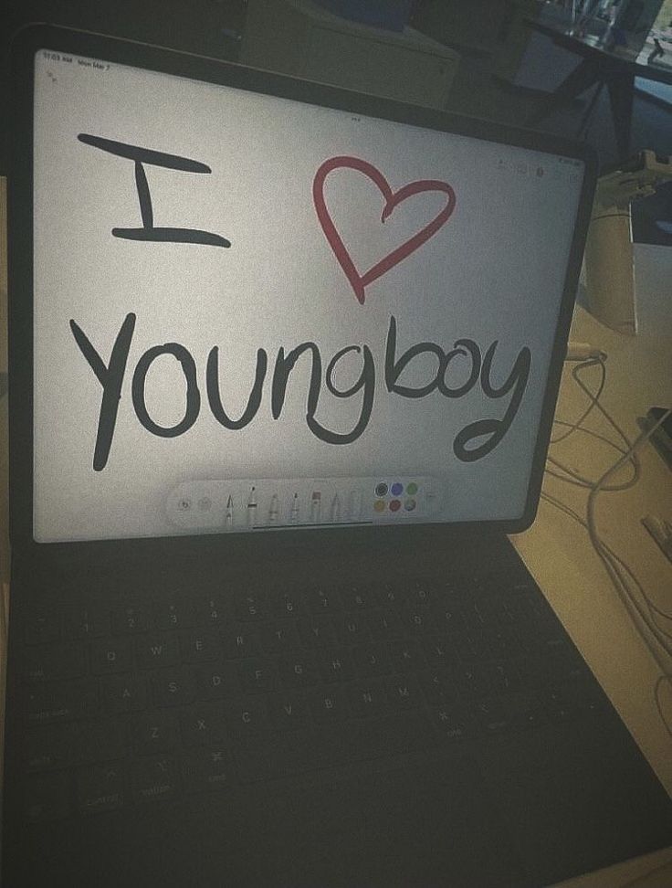 an open laptop computer sitting on top of a desk with i love young boy written on the screen