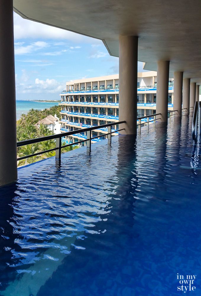 an indoor swimming pool with blue water in front of a large building and the ocean