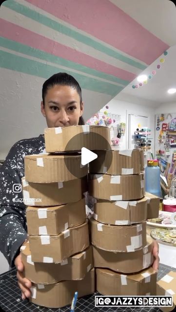 a woman is holding stacks of cardboard boxes