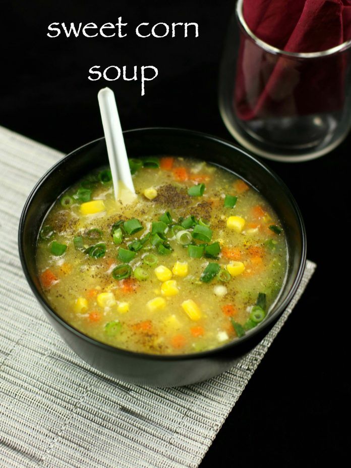 a black bowl filled with soup next to a glass of red wine and a straw