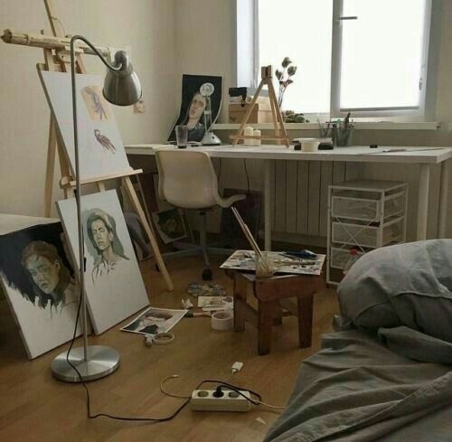 an artist's studio with easel and paintings on the floor