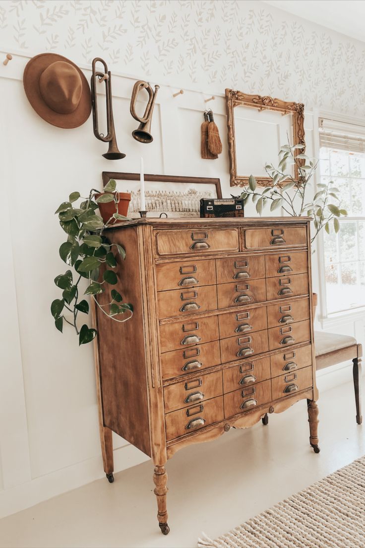 an old dresser with lots of drawers and plants on it in the corner of a room