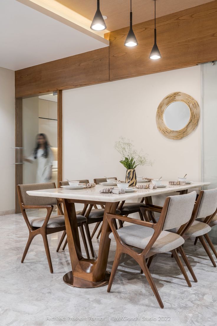 a dining room table and chairs in front of a wall with wood trimmings