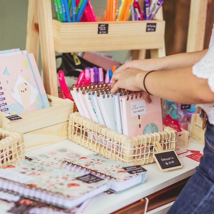 a person is holding a pen and taking notes from a notebook on a table with other items