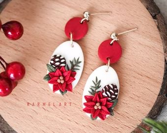 the earrings are decorated with poinsettis and pine cones on top of them