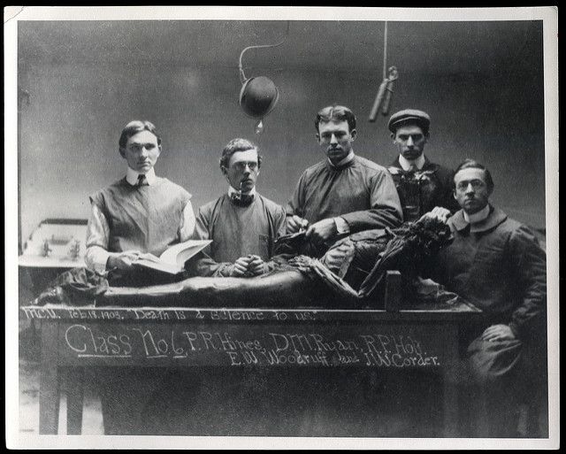 an old black and white photo of men in uniforms sitting at a table with medical equipment