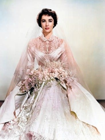 an old photo of a woman in a wedding dress with flowers on the skirt and veil