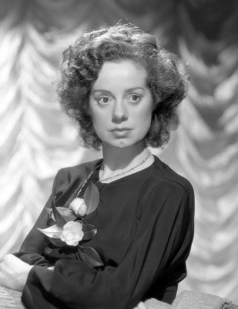 an old black and white photo of a woman holding a rose in her right hand