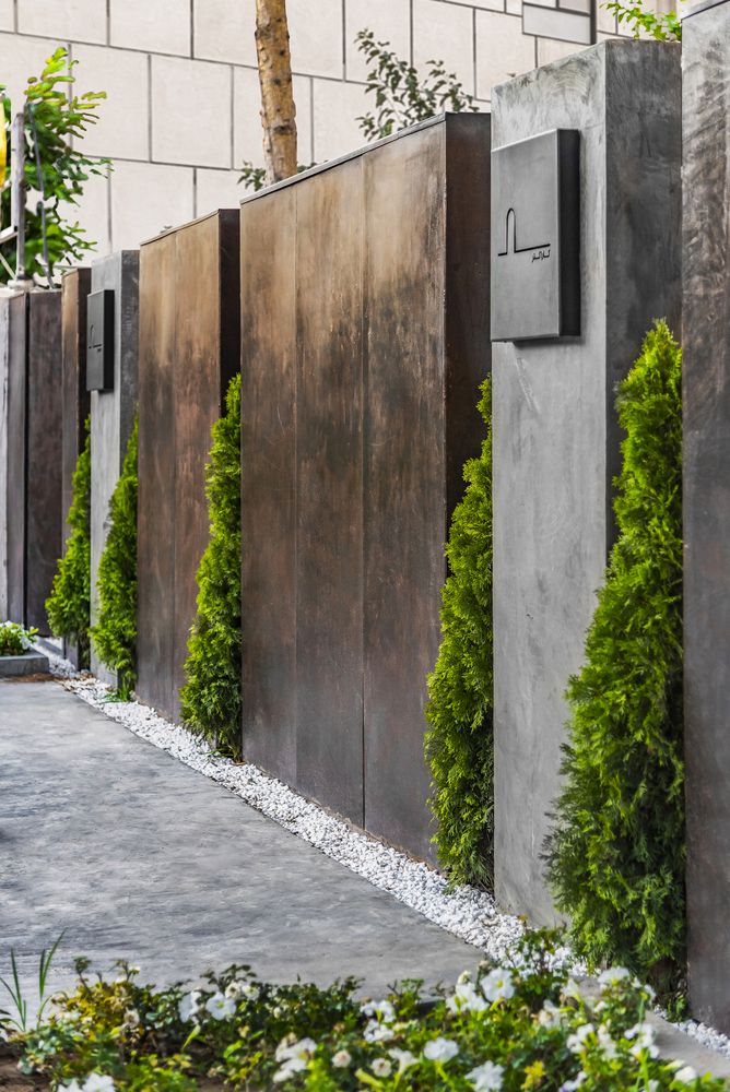 a row of metal gates with plants growing out of them on the side of a building