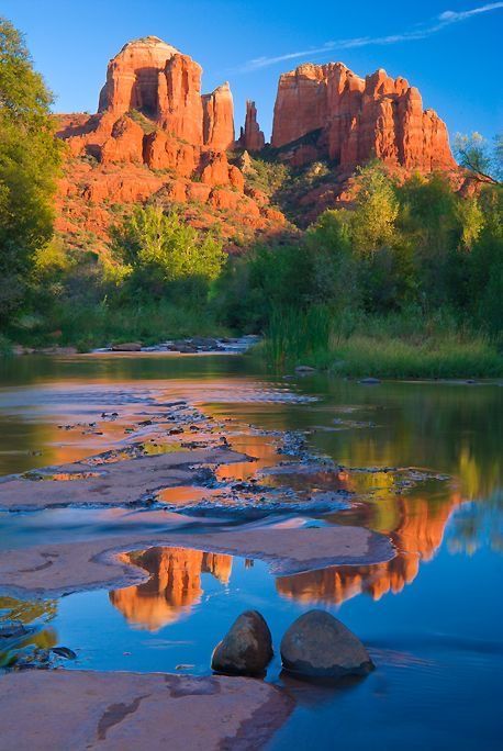 a river with rocks in the water and mountains in the backgrouds behind it