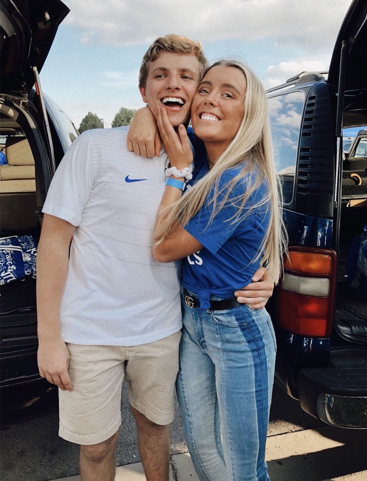 a man and woman standing next to each other in front of a car