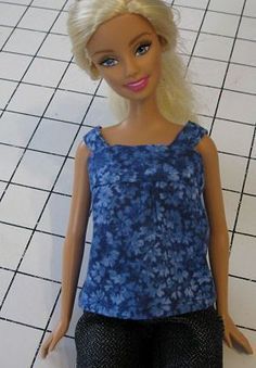 a barbie doll with blonde hair and blue top standing on tiled floor next to white tile