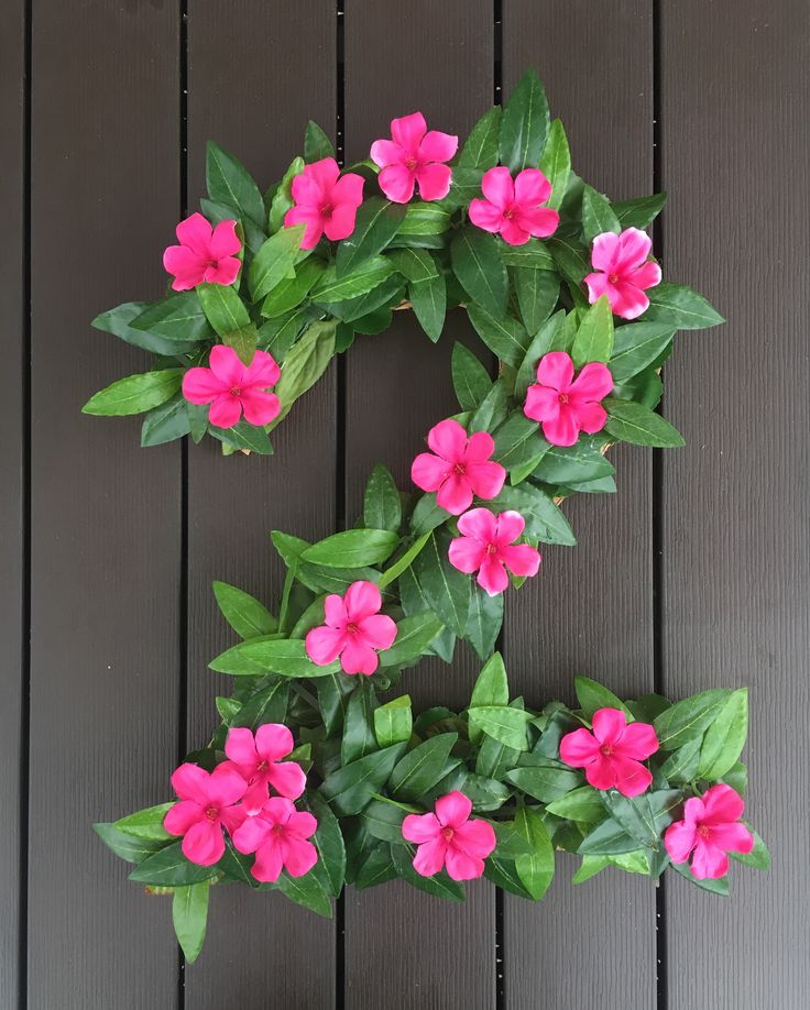 pink flowers are growing on the side of a wooden wall with green leaves around it