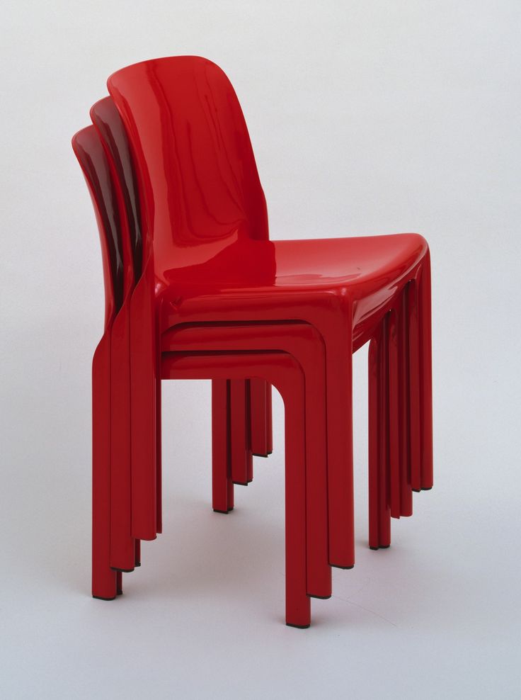 three red plastic chairs sitting next to each other on a white surface with no one around them