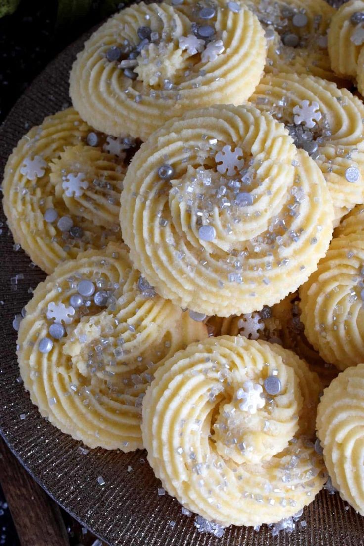 a plate filled with yellow cupcakes covered in frosting and sprinkles