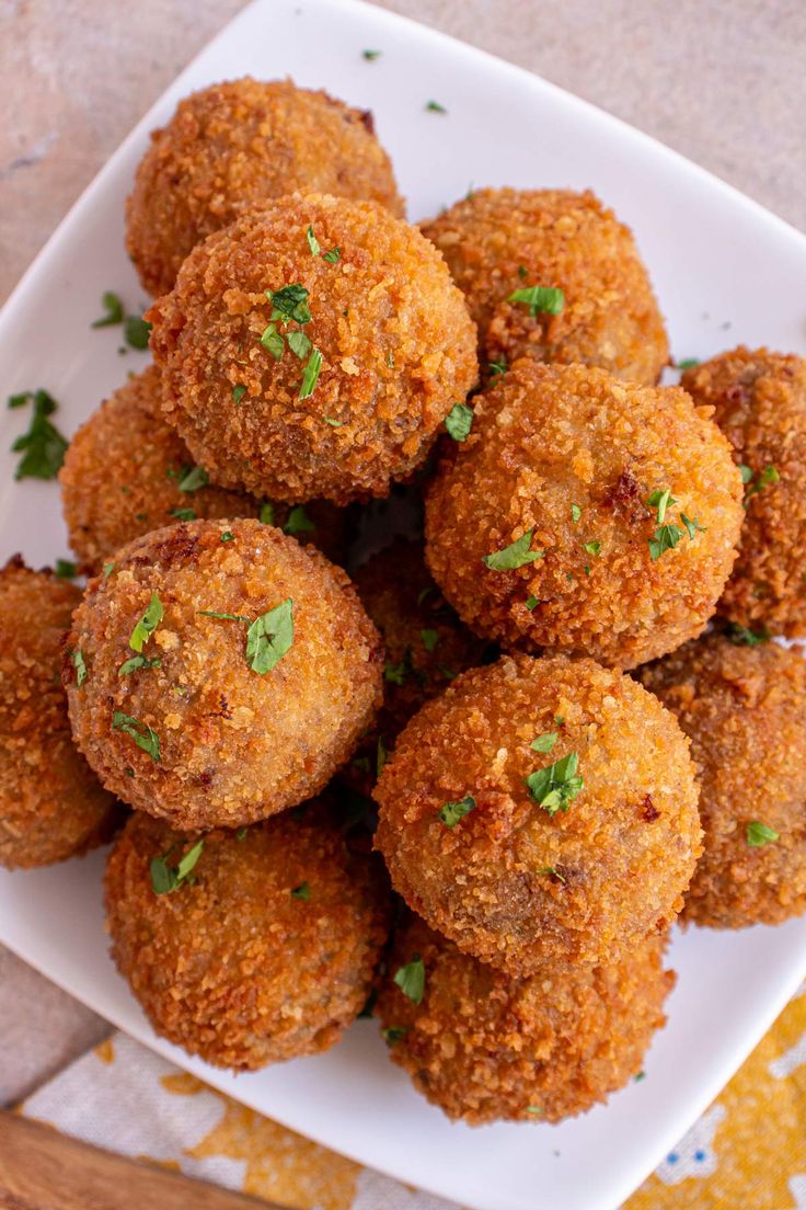 a white plate topped with meatballs covered in parmesan cheese and garnished with cilantro