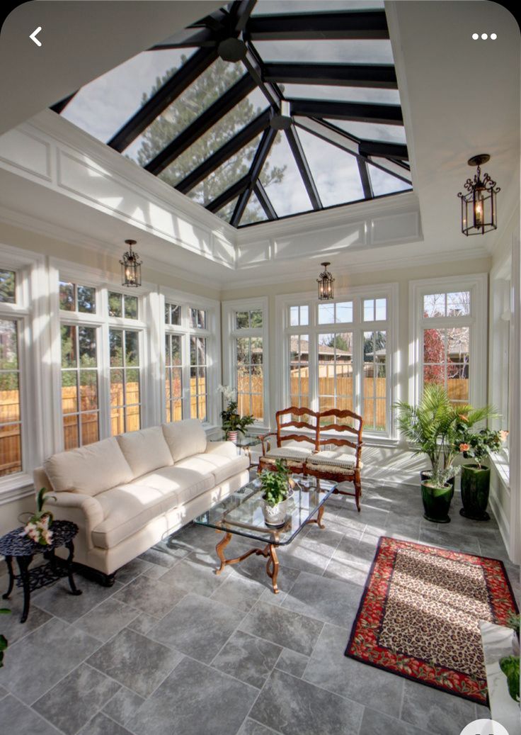 a living room filled with lots of furniture under a glass ceiling covered in light shinning