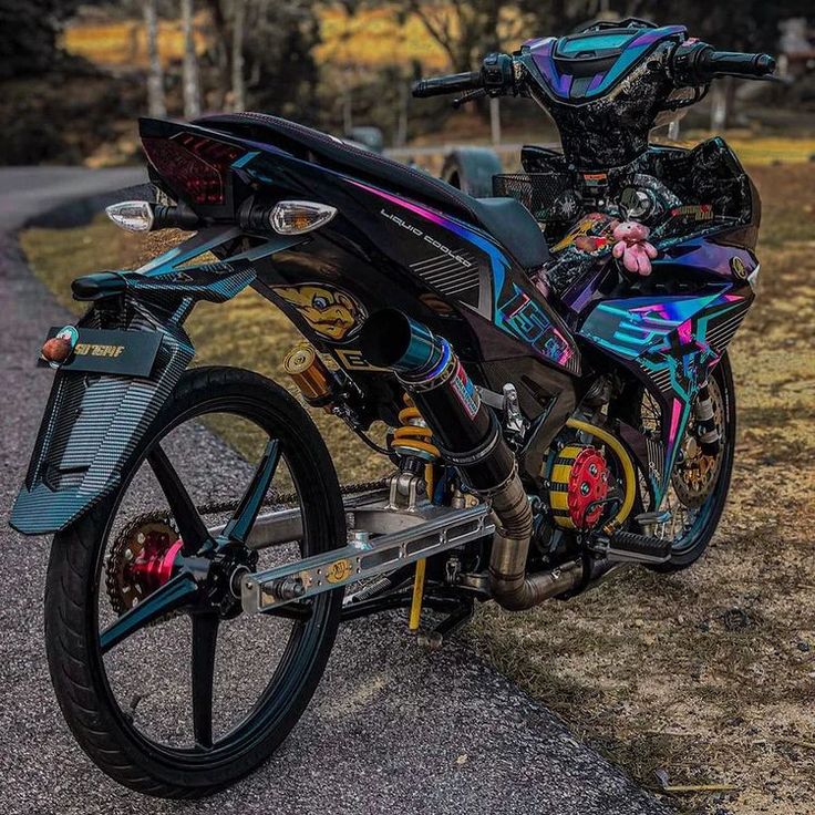 the motorcycle is parked on the side of the road in front of some grass and trees