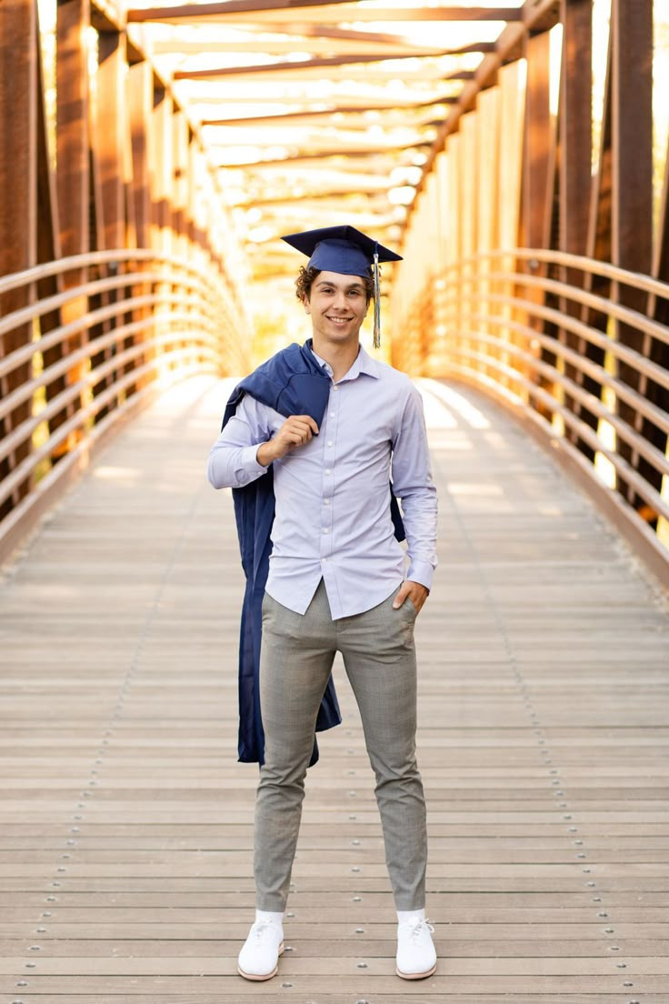 a man standing on a bridge wearing a cap and gown