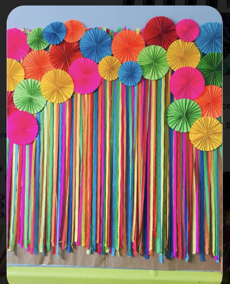 there are many colorful paper umbrellas hanging from the side of a wall with streamers attached to it