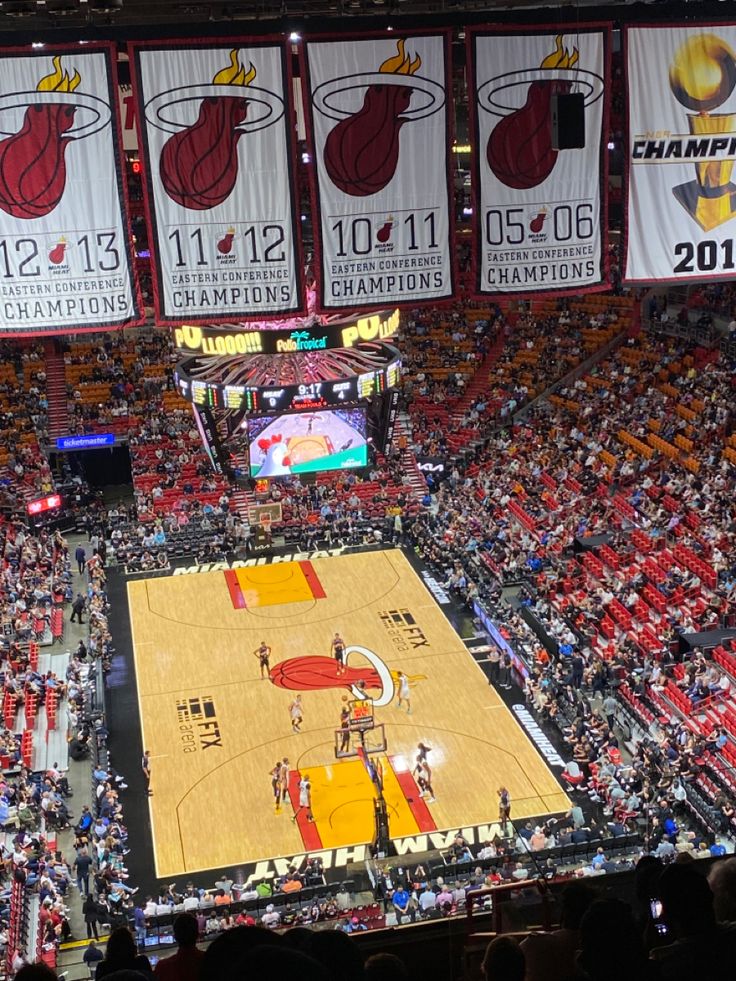 an indoor basketball game in progress with the scoreboard and seats up to 3, 000