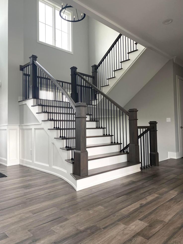 an empty living room with wood flooring and stairs leading up to the second floor