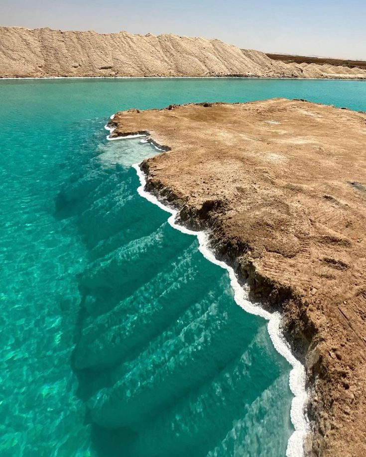 the water is crystal blue and clear in this photo, it looks like there are waves coming out of the sand