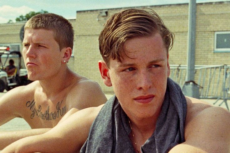 two young men sitting next to each other in front of a fire hydrant and building