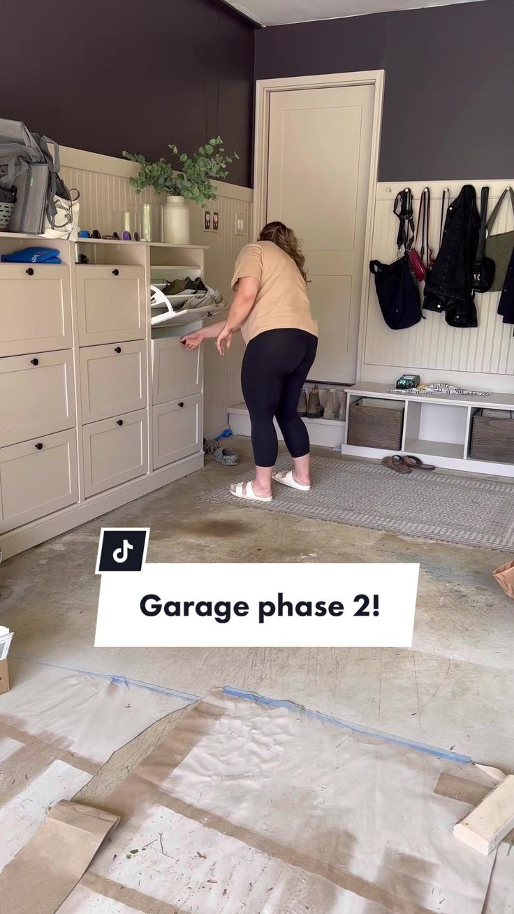 a woman standing in the middle of a room with garage phase 2 written on it