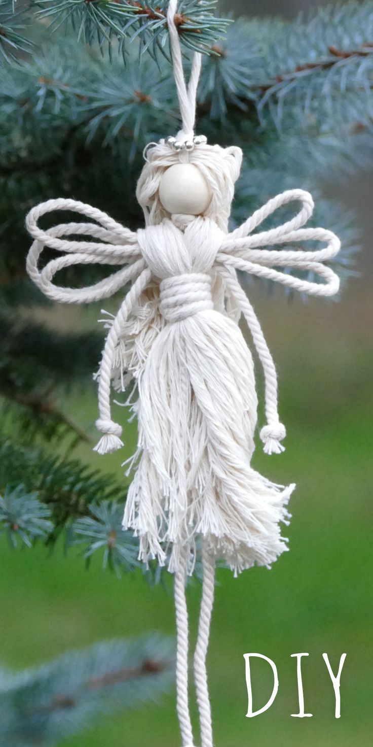 a white angel ornament hanging from a pine tree with the words diy on it