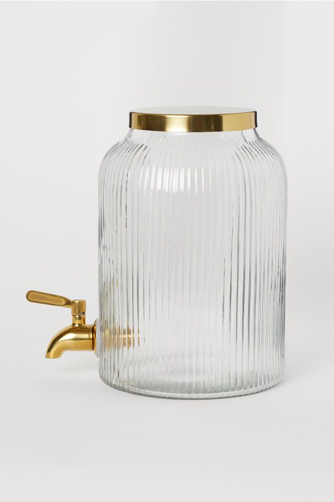 a clear glass jar with a gold lid and brass spigot on the side