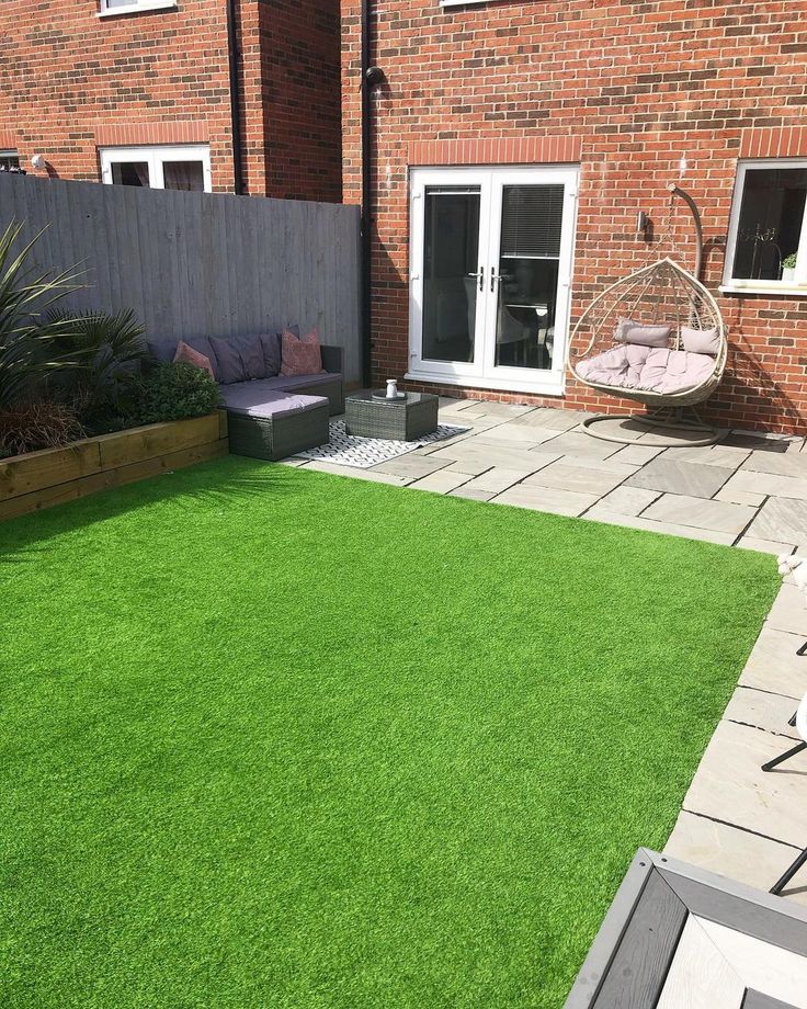 an outdoor area with grass and furniture in the back yard, surrounded by brick buildings