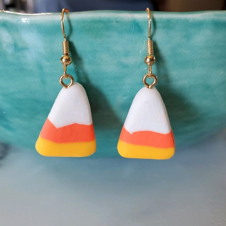 the earrings are made out of plastic and have an orange, white, and yellow triangle design